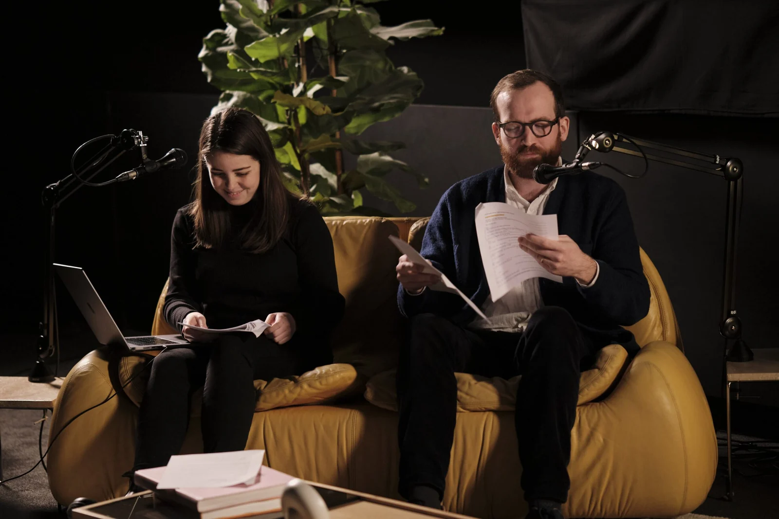Two hosts recording from scripts in the armchairs