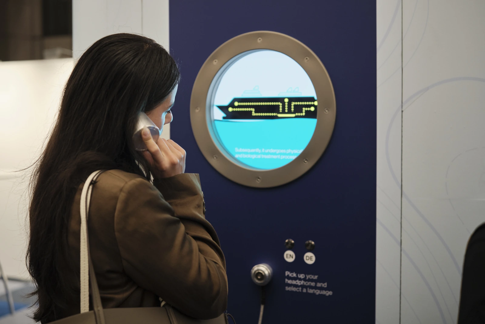 A visitor listening on a handset at one of the porthole screens