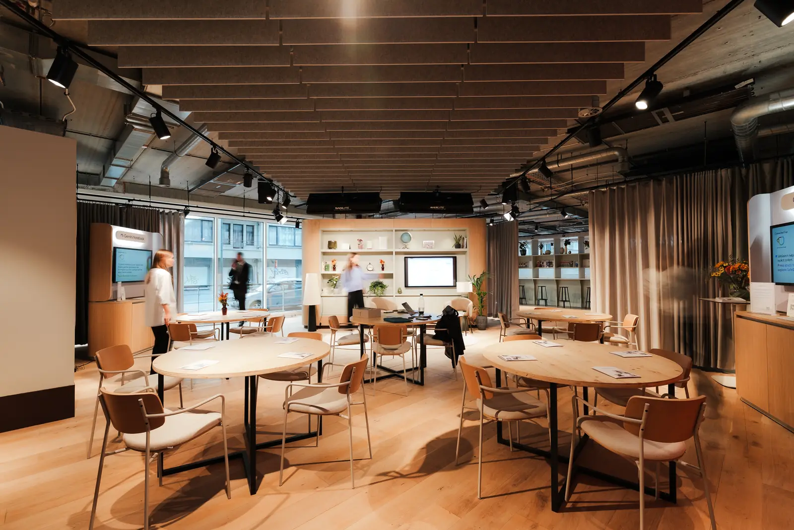 The room set with round tables, guests working and talking by the windows