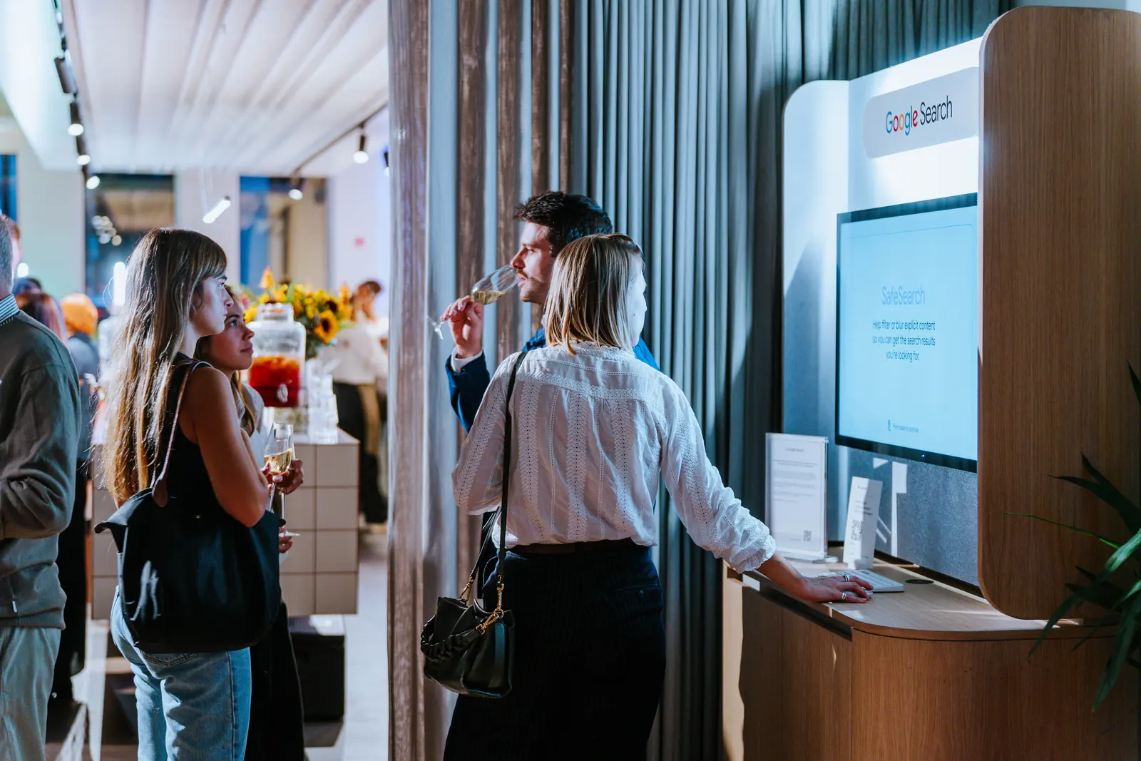 Two guests trying a Google Search demo station with drinks in hand